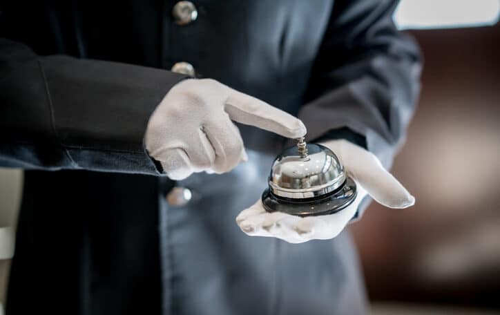 Close up of unrecognizable bell boy at a hotel ringing the bell